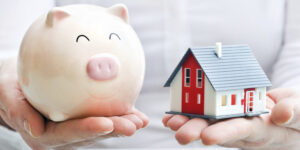 Hands holding piggy bank and house model